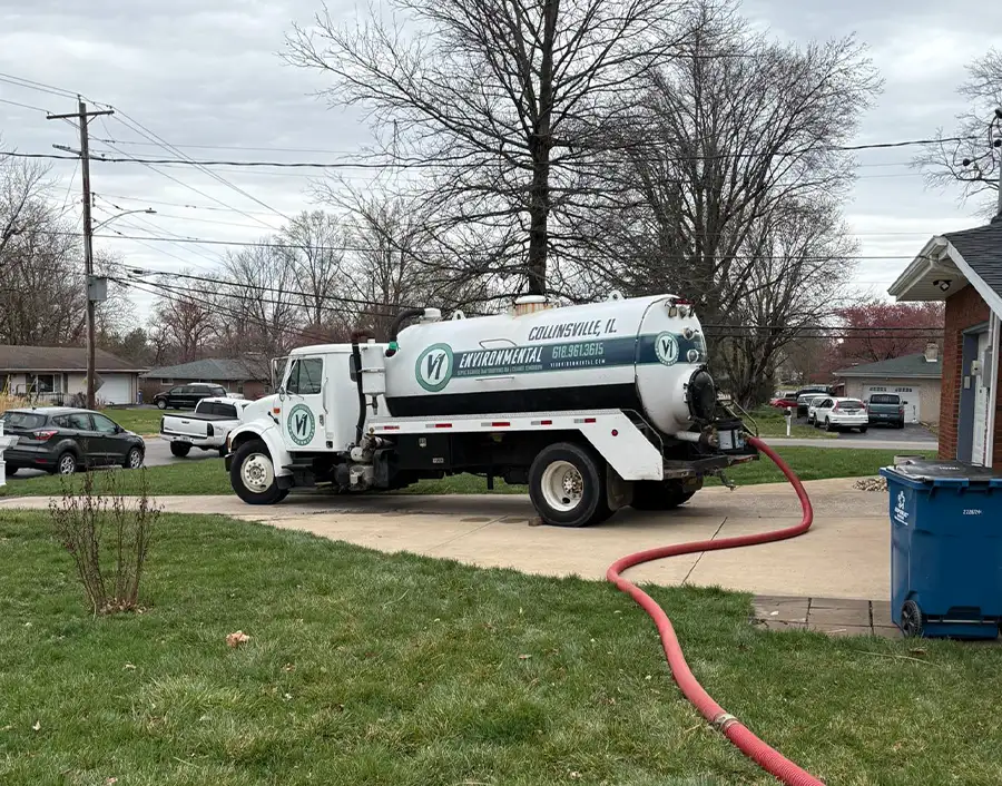 V1 Environmental company truck and septic pump parked in driveway of residential home, pump hose leading away - Southern Illinois