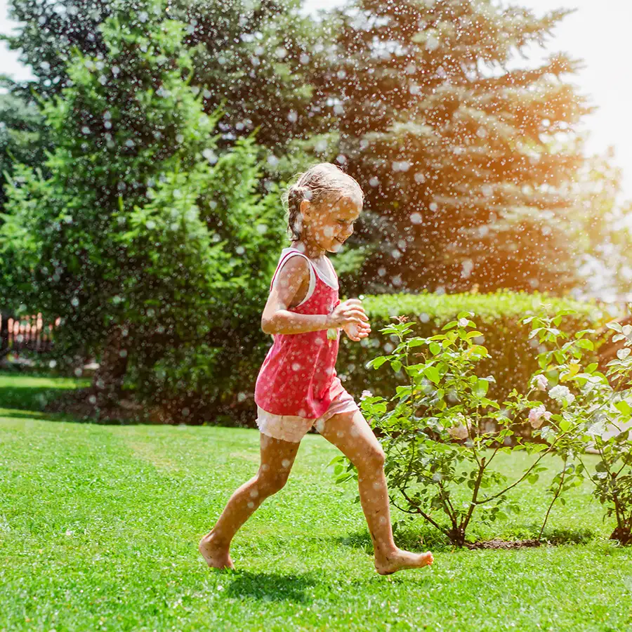 Benefits of Routine Septic Maintenance and Pumping in Southern Illinois - little girl enjoying backyard, running around in sprinklers on a hot day